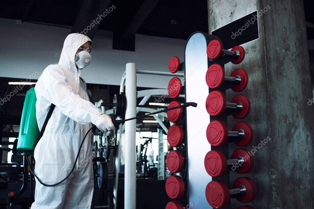 Addetto alle pulizie che sanifica gli attrezzi in palestra