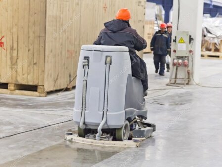Operatore di pulizie con DPI e aspiratore industriale in un ambiente post cantiere