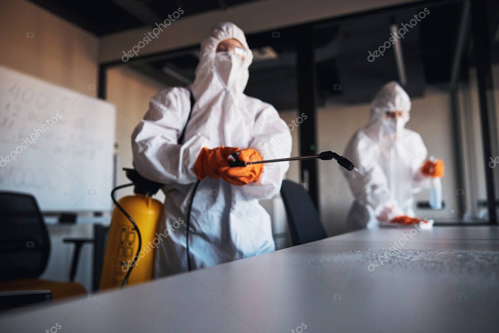 Operatore che sanifica una sala riunioni con prodotti professionali